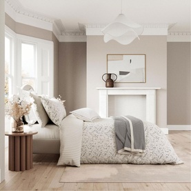Bedeck Belfast Ayda Square Pillowcase in ivory, styled on a bed with floral duvet in a neutral bedroom setting