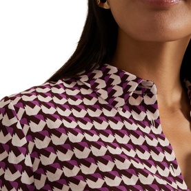 Model wearing Phase Eight Gina Printed Shirt in multi geometric print, classic collar visible, paired with gold earrings