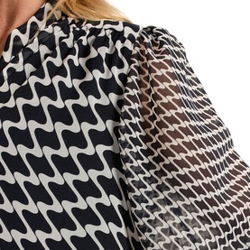 Model wearing Phase Eight Suki Printed Pussybow Mini Dress in blue, showing geometric wave print and semi-sheer blouson sleeves at neckline