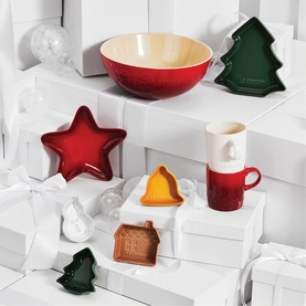 Le Creuset Stoneware Holly Mug 350ml in red and white with seasonal holly motif, styled with festive stoneware dishes and bowls in red and green