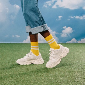 Model with Eat My Socks Soft Gruy&egrave;re Socks in yellow stripe crew style, styled with white chunky trainers and cuffed jeans