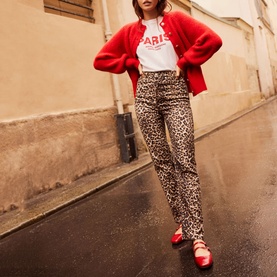Model wearing Mint Velvet Military Rib Knit Cardigan in red, styled with a Paris slogan tee and leopard print trousers