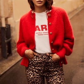 Model wearing Mint Velvet Military Rib Knit Cardigan in red with gold buttons, styled with white graphic tee and leopard print jeans