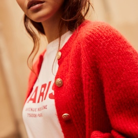 Model wearing Mint Velvet Military Rib Knit Cardigan in red with gold buttons, styled over a white graphic tee