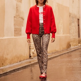 Model wearing Mint Velvet Military Rib Knit Cardigan in red with balloon sleeves, styled with leopard print trousers and red shoes