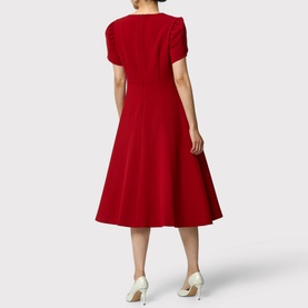 Model wearing Helen McAlinden Vera Fit-And-Flare Dress in red, midi length with puffed sleeves and flared skirt, styled with white heels