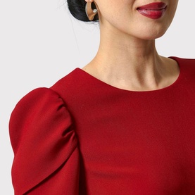 Model wearing Helen McAlinden Vera Fit-And-Flare Dress in red, featuring round neckline and short puffed sleeves, with gold drop earrings