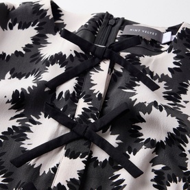 Mint Velvet Abstract Tiered Mini Dress in black monochrome print, showing bow detail and back zip fastening close-up
