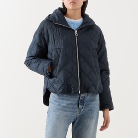 Model wearing Marc O Polo Quilted Cape Jacket in blue, featuring diamond quilting, hood, and front zip, styled with light blue jeans