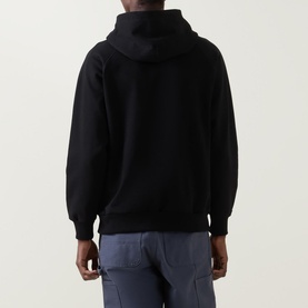 Model wearing Deus Ex Machina Pill Logo Hoodie in black, rear view, showing drawstring hood and ribbed cuffs, styled with blue jeans