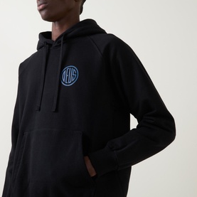 Model wearing Deus Ex Machina Pill Logo Hoodie in black with blue circular chest logo, drawstring hood, and front pouch pocket