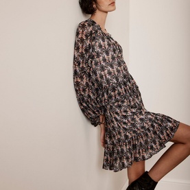 Model wearing Mint Velvet Ruffle-Detail Printed Dress in beige, floral print, V-neck, puffed sleeves, tiered mini skirt