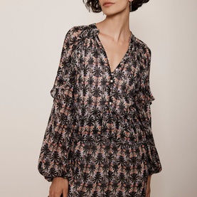 Model wearing Mint Velvet Ruffle-Detail Printed Dress in beige, black floral print, V-neckline, puffed sleeves and tiered skirt