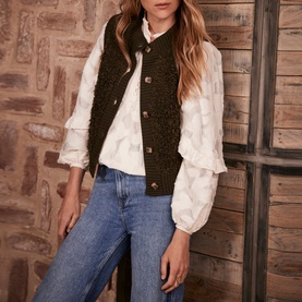 Model wearing Mint Velvet Green Boucl&eacute; Gilet with button fastening and ribbed trims, styled with white ruffle blouse and blue jeans