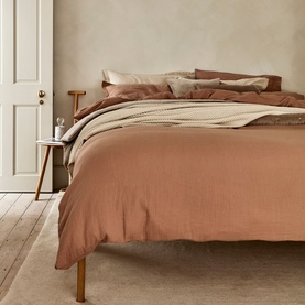 Christys 200 Thread Count Retreat Fitted Sheet in brown, styled on a bed with matching duvet and neutral pillows in a calm bedroom setting