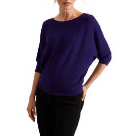 Model wearing Phase Eight Cristine Knitted Sweater in purple with batwing three-quarter sleeves and slash neckline, styled with black trousers