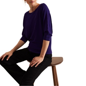 Model wearing Phase Eight Cristine Knitted Sweater in purple with batwing three-quarter sleeves and slash neckline, styled with black jeans