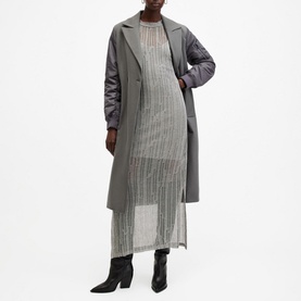 Model wearing All Saints Giana Open-Stitch Dress in grey with metallic yarn detail, styled with a grey coat and black boots