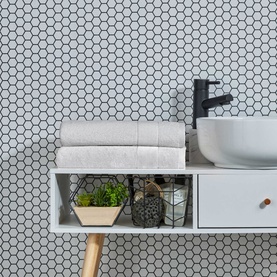 Christys Prism Towel Whitewash in white, 100% Turkish cotton, folded and styled on a bathroom shelf with plant decor