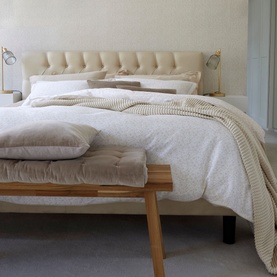Christys Daisy Meadow Duvet Set Hazelnut in brown cotton sateen with printed design and piped trim, styled on a wooden bed frame