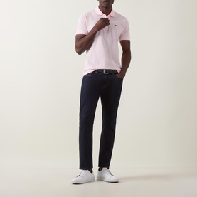 Model wearing Lacoste Heritage Logo Piqu&eacute; Polo Shirt in light pink with navy slim-fit trousers and white trainers