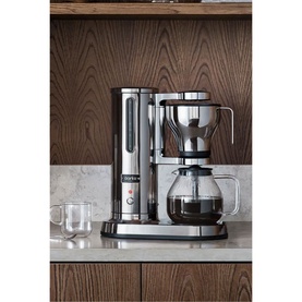 Aarke Coffee Brewer Stainless Steel in silver, with glass carafe, on marble countertop against wood-panelled cabinetry