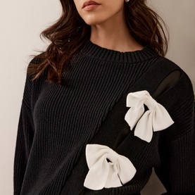 Model wearing Mint Velvet Bow Knit Sweater in black with white oversized bow details on ribbed crew-neck cashmere-blend knit