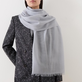 Model wearing Fraas Frayed Logo Scarf in grey wool with frayed ends, styled over a dark speckled coat