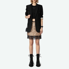 Model wearing Zadig Sequin Mini Skirt in gold with lace hem trim, styled with black blazer, crop top, and lace-up boots