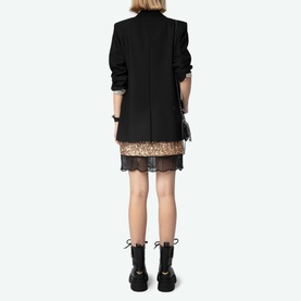 Model wearing Zadig Sequin Mini Skirt in gold with lace hem trim, styled with black blazer and lace-up boots, seen from behind