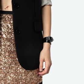 Model wearing Zadig gold sequin mini skirt with lace trim hem, styled with black waistcoat and chunky black watch