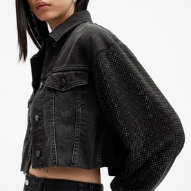 Model wearing All Saints Anders Embellished Cropped Denim Jacket in black with crystal-embellished sleeves, button front, and frayed hem