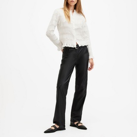 Model wearing All Saints Meg Textured Shirt in white with frill hemline, styled with black faux-leather trousers and Mary Jane flats