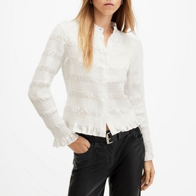 Model wearing All Saints Meg Textured Shirt in white with frill hemline and long sleeves, styled with black leather trousers