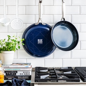 Blue Diamond Non-Stick Frypan 30cm in blue, hanging in kitchen above gas hob with stack of books and herb plant nearby