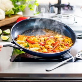 Blue Diamond Non-Stick Frypan 30cm in blue, cooking a colourful vegetable stir-fry on a hob, with steam rising from the pan