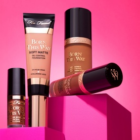 Too Faced Travel Size Born This Way Super Coverage Concealer in Natural Beige, shown alongside Born This Way foundation products on pink stepped