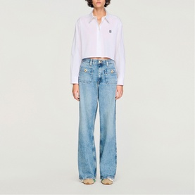 Model wearing Sandro Patch Pocket Wide Leg Jeans in blue jean, styled with a white cropped shirt. Wide leg silhouette with embellished patch pockets.