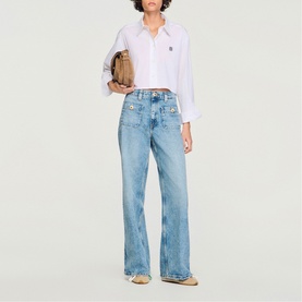 Model wearing Sandro Patch Pocket Wide Leg Jeans in blue jean, styled with a white shirt and carrying a tan bag.