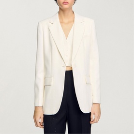 Model wearing Sandro Sequin Suit Blazer in clear, single-breasted with long sleeves, styled with navy trousers and white top.