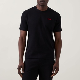 Model wearing Hugo Austin Logo Pyjama Top in black, featuring red logo detail, round neck and short sleeves, paired with black bottoms.