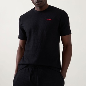 Model wearing Hugo Austin Logo Pyjama Top in black, waffle-finish fabric, round neck, short sleeves, with matching black lounge bottoms.