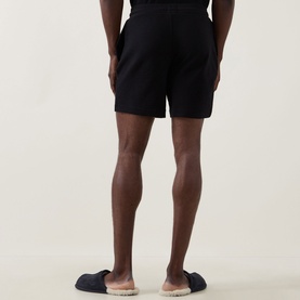 Model wearing Hugo Austin Logo Drawstring Lounge Shorts in black waffle-finish fabric, rear view, styled with grey sliders.