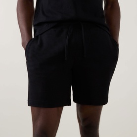 Model wearing Hugo Austin Logo Drawstring Lounge Shorts in black, waffle-knit fabric with drawstring waist and side pockets, styled with black T-shirt