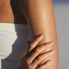 Close-up of sun-kissed glowing skin on arm and torso, styled to showcase Sol De Janeiro GlowMotions Copacabana Bronze Glow Oil finish