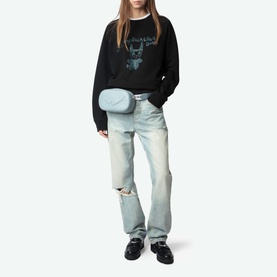 Model wearing Zadig Supper Printed Pullover Sweatshirt in black with rock graphic, styled with light wash ripped jeans and a pale blue crossbody bag