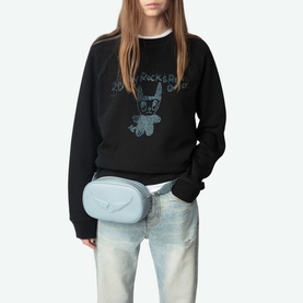 Model wearing Zadig Supper Printed Sweatshirt in black with Rock N Roll devil graphic, styled with light blue belt bag and wide-leg jeans