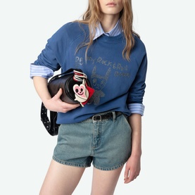 Model wearing Zadig Upper Devil Queen Sweatshirt in blue with rhinestone detailing, styled with denim shorts, carrying a novelty clutch bag