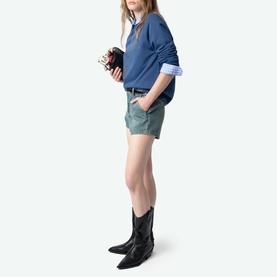 Model wearing Zadig Upper Devil Queen Sweatshirt in blue with crew neck, styled with khaki shorts, black cowboy boots, and small black bag