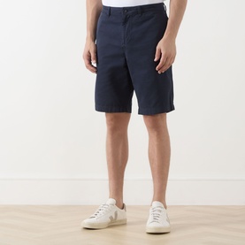 Model wearing Lyle & Scott Eagle Logo Chino Shorts in Dark Navy with white low-top trainers. Four-pocket chino style with belt loops.